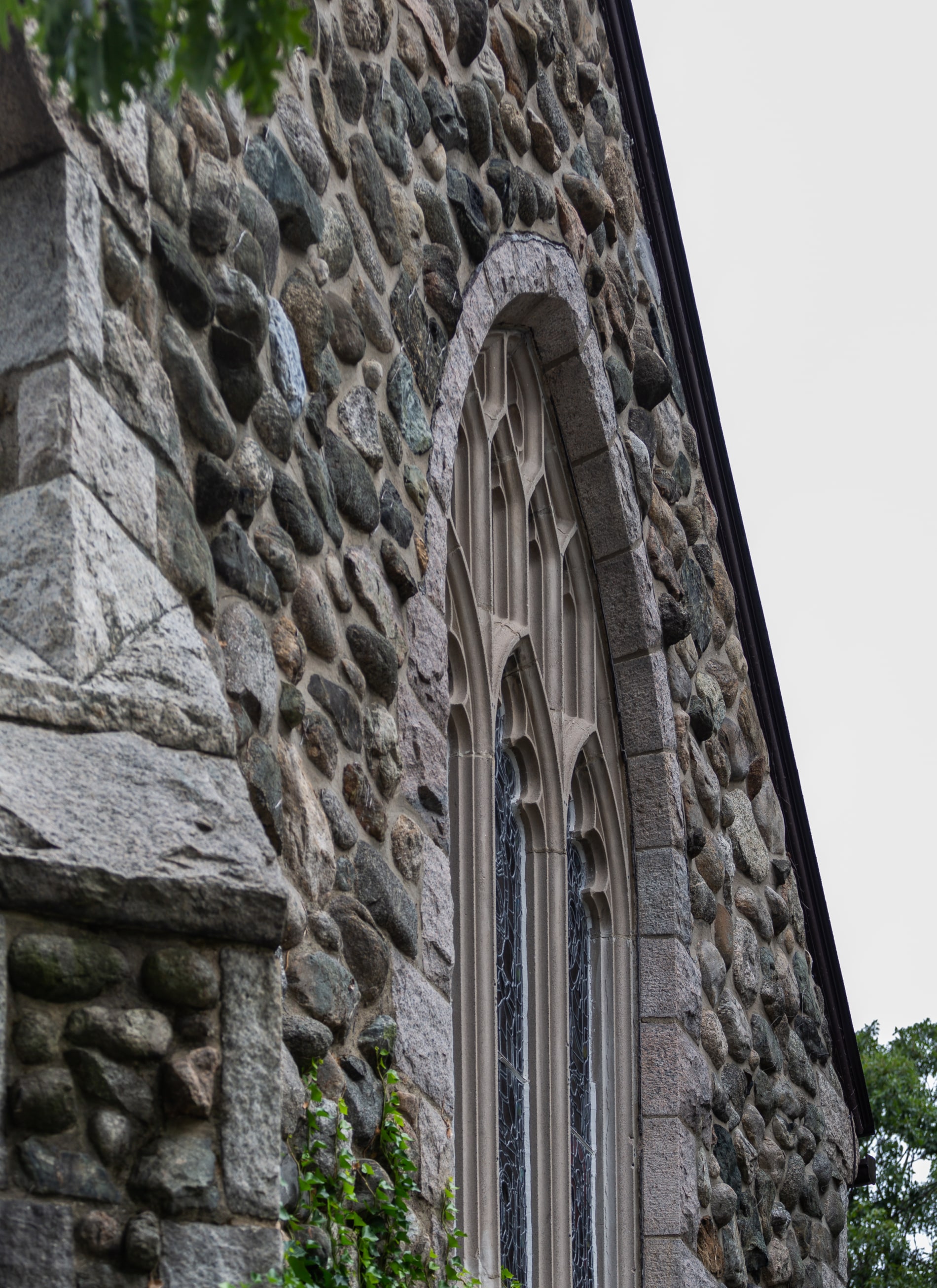 Facade of a stone church with arched stainmed glass windows