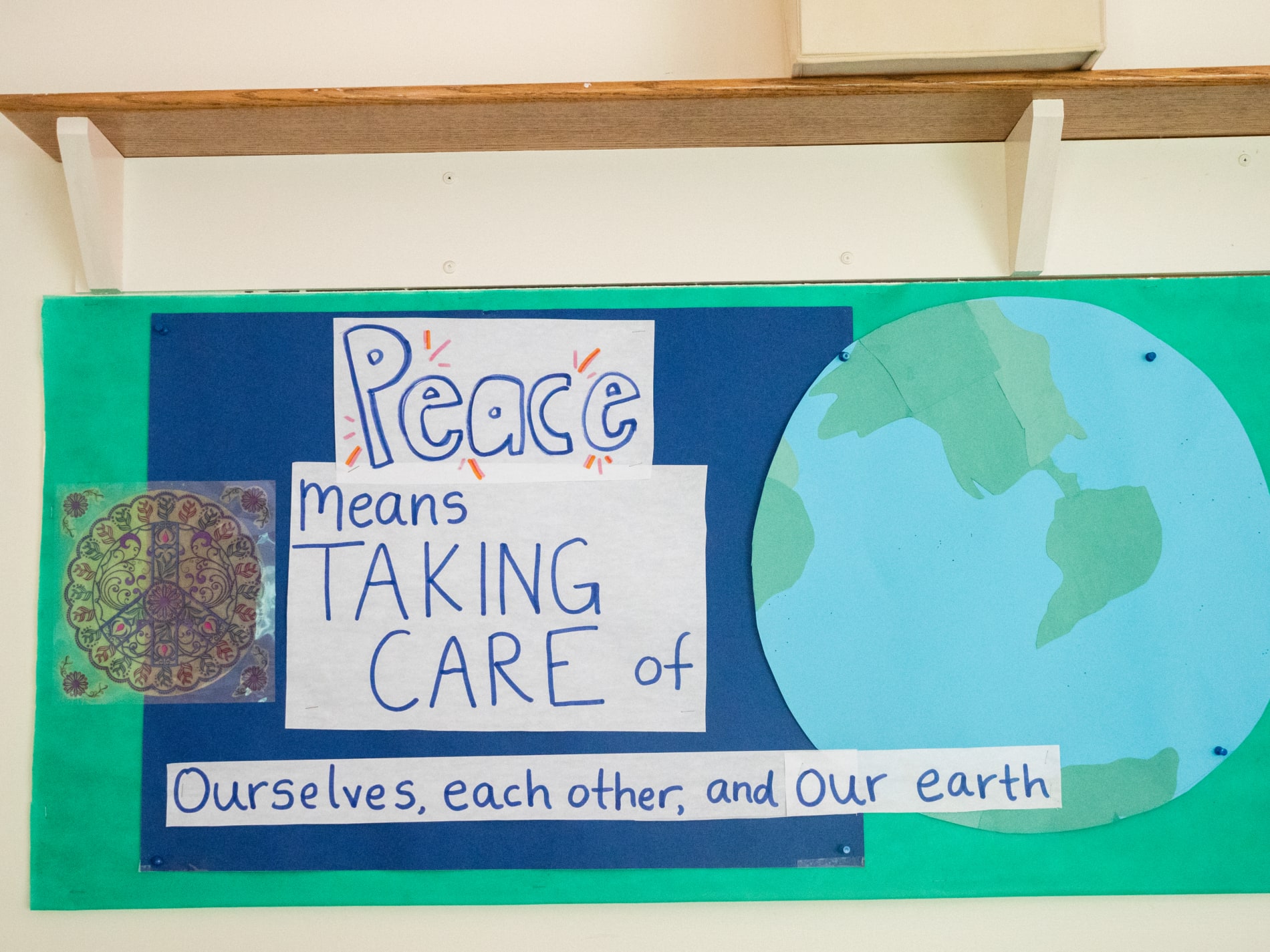 Poster with a picture of the earth that says "Peace means taking care of ourselves, each other, and our earth."
