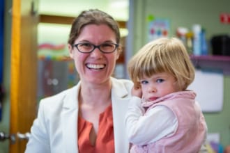 A woman smiling while holding her daughter